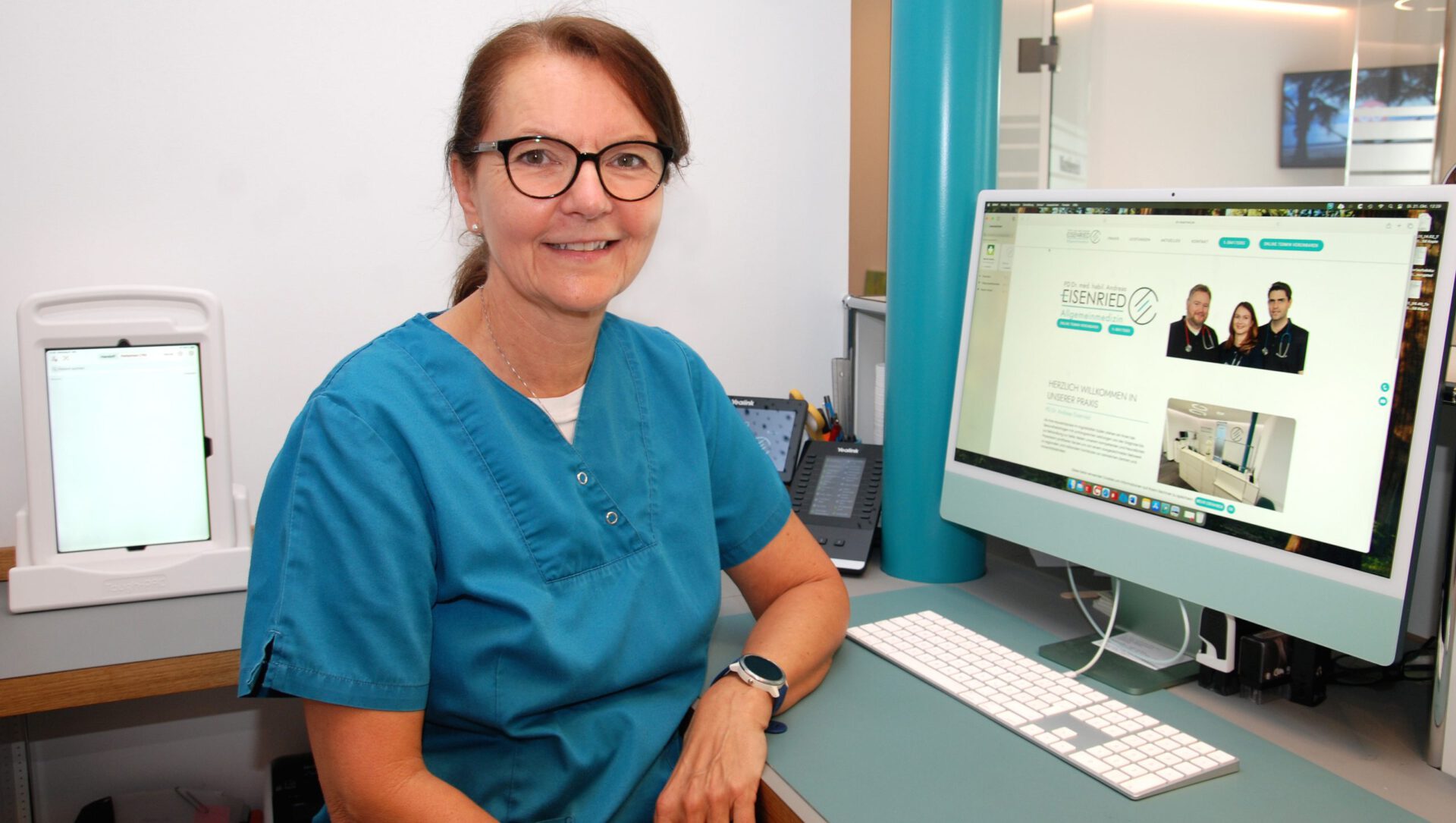 Eine Mitarbeiterin sitzt am Empfang der Praxis Dr. Eisenried